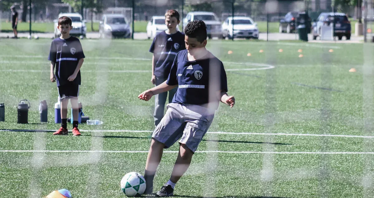 kid on field kicking soccer ball
