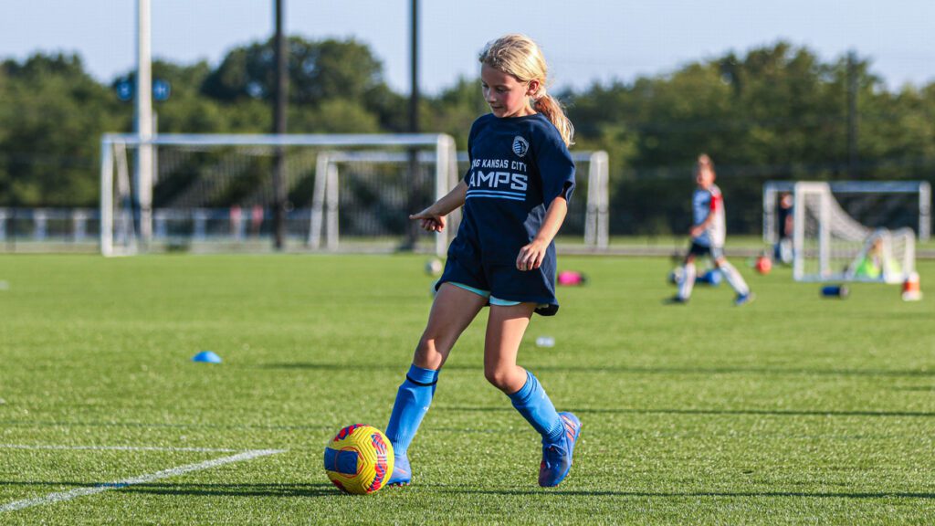 girl kicking a soccer ball at the olathe camp